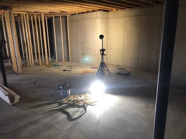 Partition walls framed out in a basement, lit by a work light