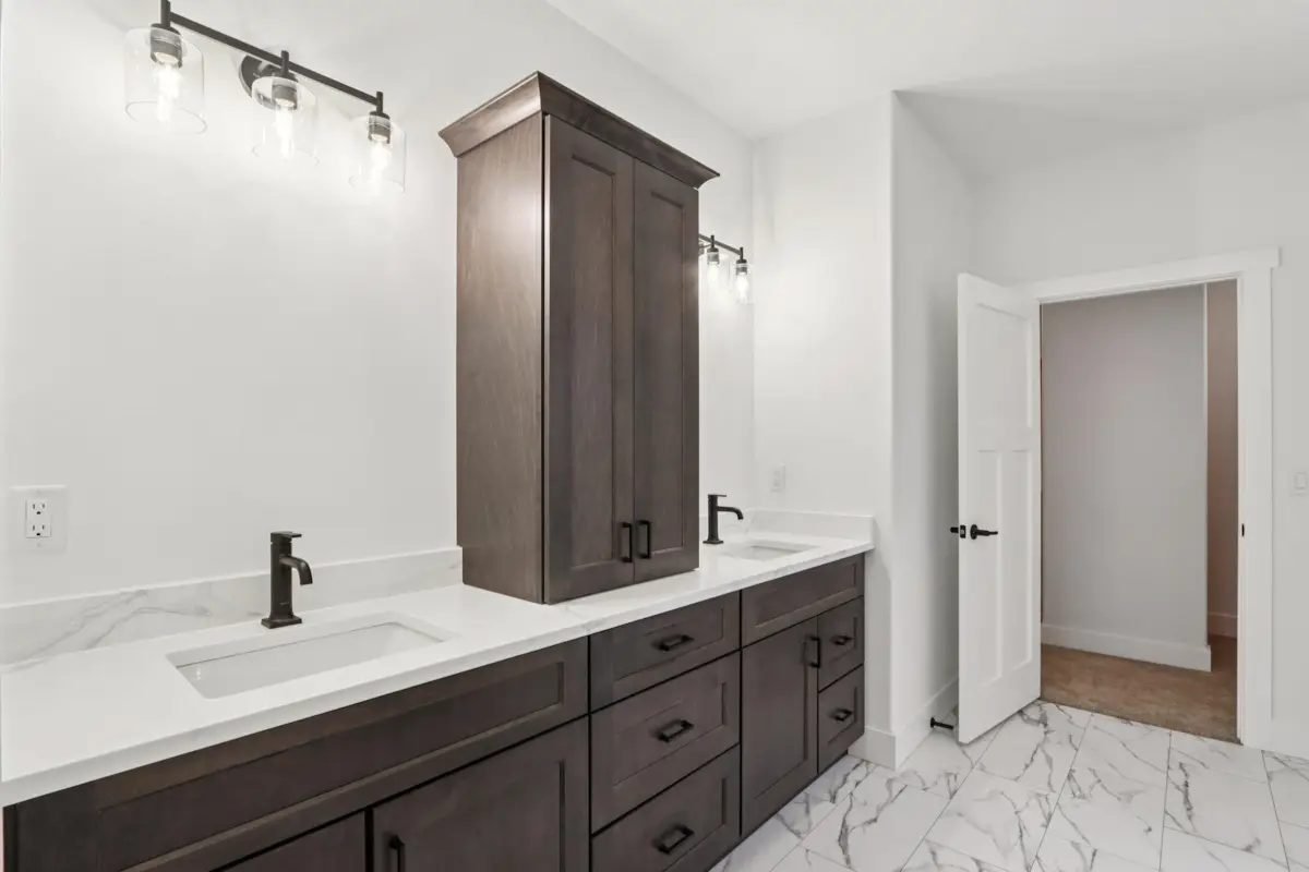 Bathroom with a dark double vanity, tower cabinet, and marble-look tile floor