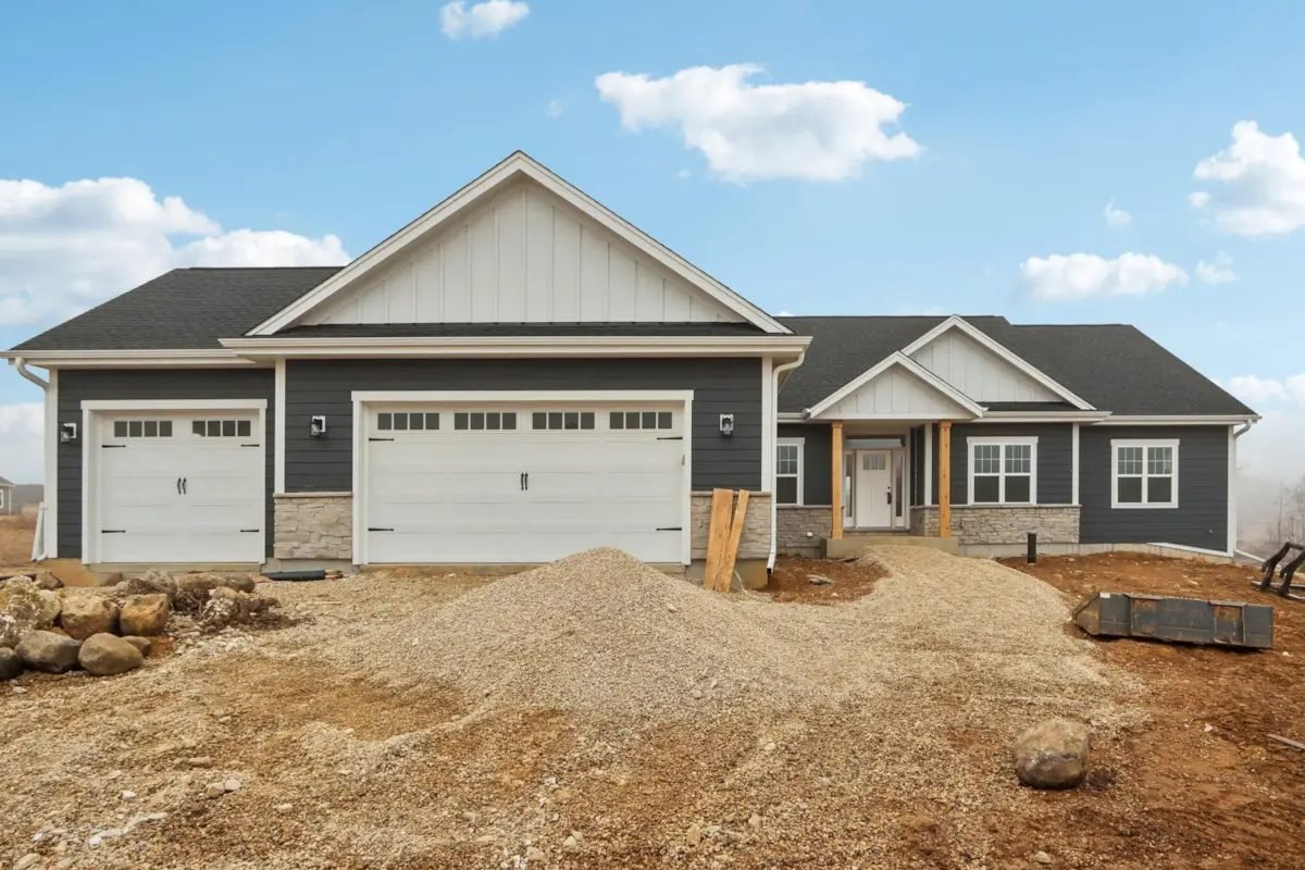 Front elevation of the Oak Ridge ranch: charcoal board-and-batten and lap siding, stone wainscot, and a three-car attached garage
