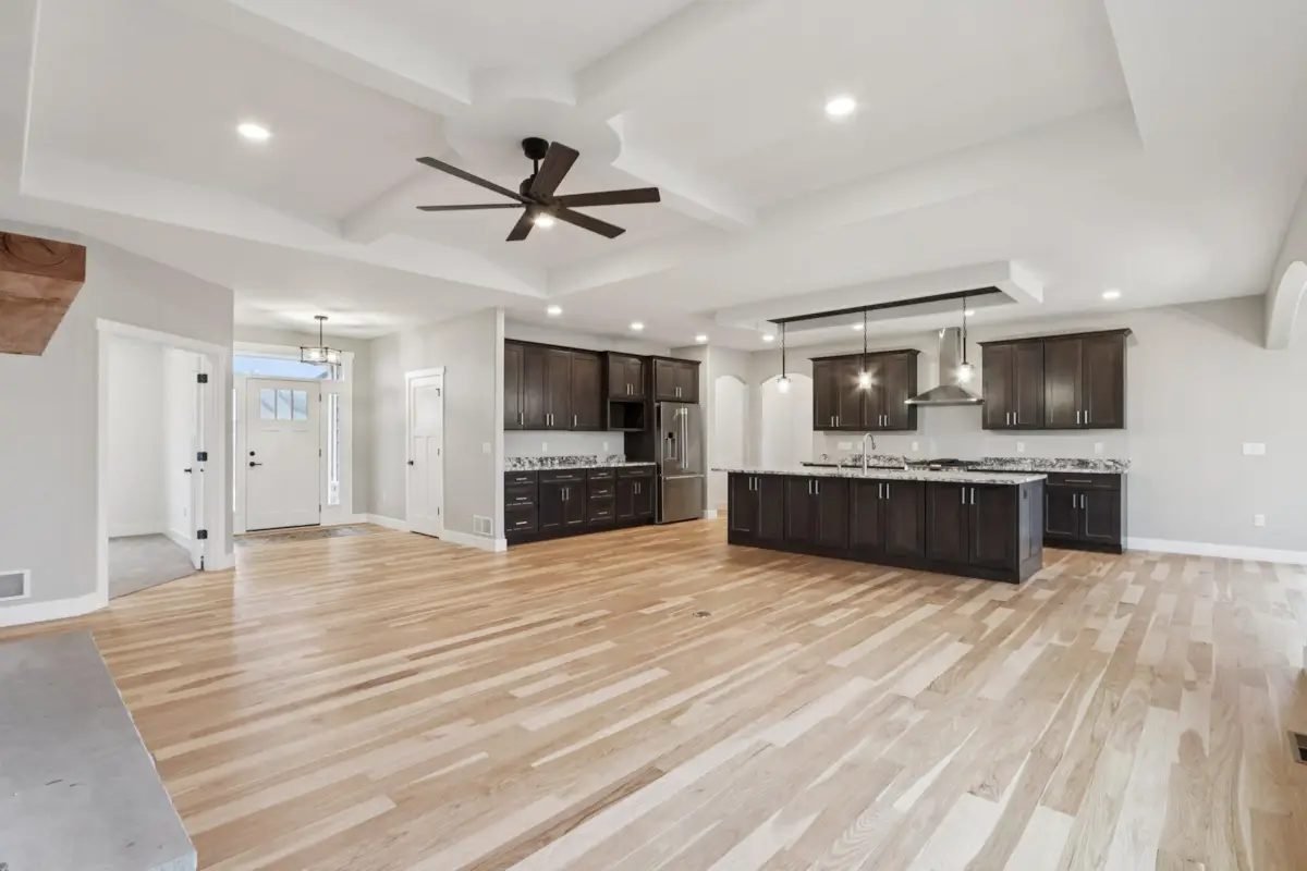 Open kitchen with a dark shaker island, white oak flooring, and a coffered ceiling