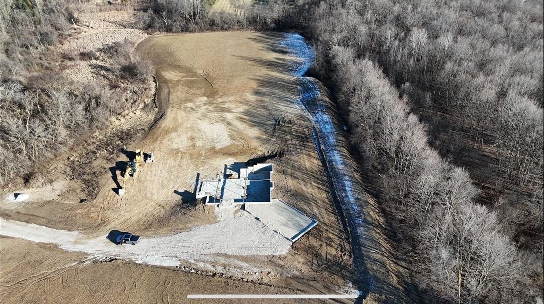 Excavated building site backing onto woodland, with footings laid out