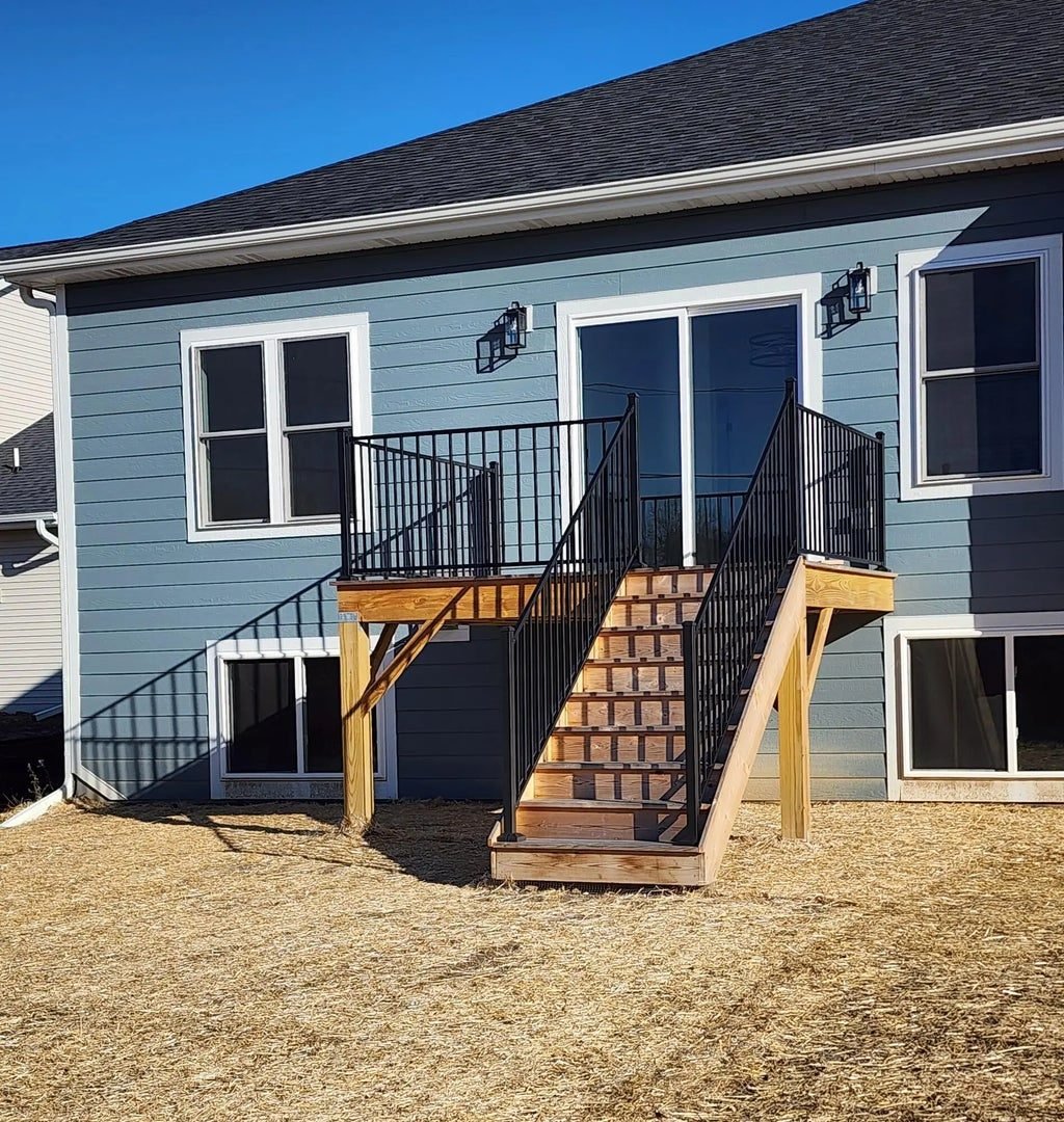 Rear elevation showing the walkout, with the exterior stair framed and railed and lower-level windows set