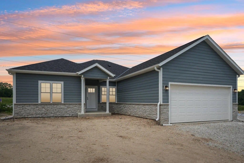 The Tess ranch built by G&A Construction, blue lap siding over a stone skirt at sunset