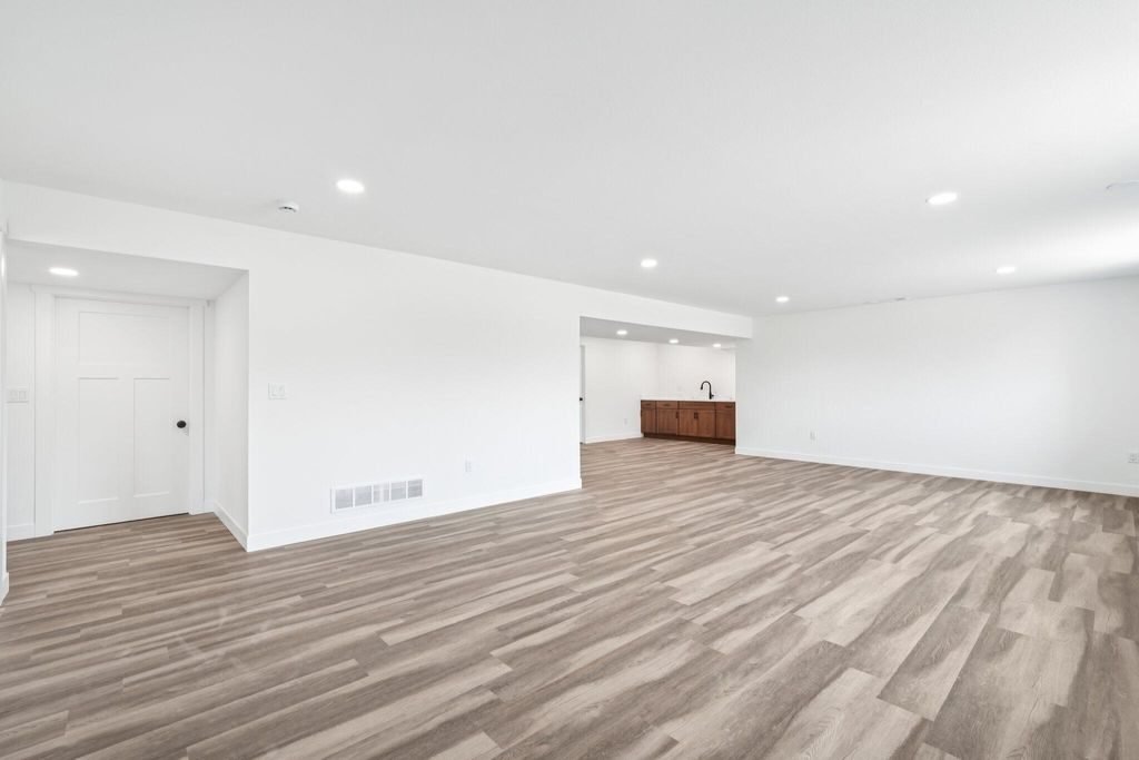 Finished lower level, open plan with plank flooring and recessed lighting