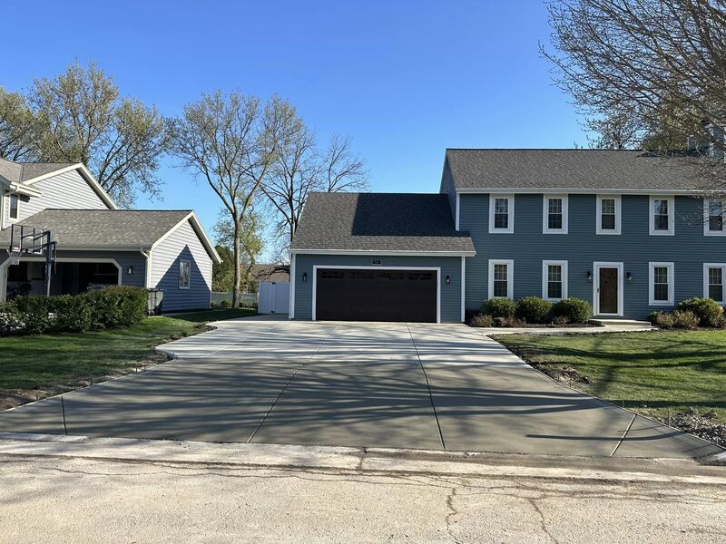 Completed broom-finish concrete driveway at same blue colonial home
